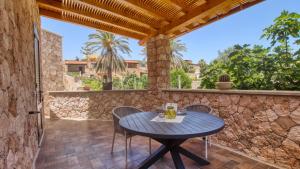 d'une terrasse avec une table et des chaises ainsi qu'un mur en pierre. dans l'établissement Residence Il Corallo - Guitgia, à Lampedusa