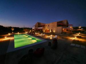 een groot zwembad 's nachts met een gebouw bij Abeloessa Methonian Hospitality in Methoni