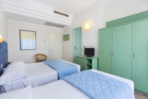 a hotel room with two beds and a desk at Bellariva Feeling Hotel in Rimini