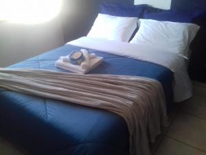 Una cama con reloj y toallas. en Casa Praia Alegre, en Penha