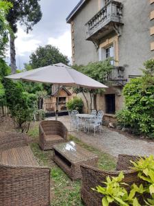 patio con tavolo, sedie e ombrellone di Villa La Fontaine Sarlat La Caneda a Sarlat-la-Canéda