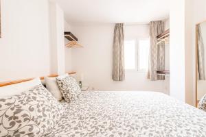 a white bedroom with a large bed and windows at Calas Beach Corralejo in Corralejo