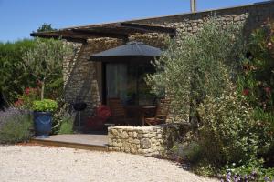 a patio with an umbrella and a table and chairs at Gite Les Lavandes in Vaison-la-Romaine