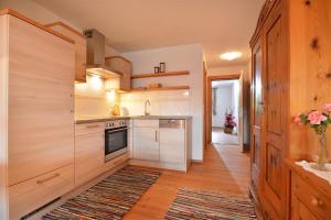 - une cuisine avec des placards blancs et un tapis au sol dans l'établissement Apartement Vorderlaiming, à Söll
