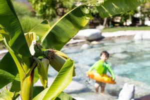 a boy in a raft in a river with a banana tree at Kreuzwegerhof Nals - Historic Nature Stay with Pool near Meran & Bozen in Nalles