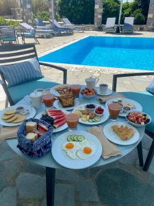 una mesa con alimentos para el desayuno junto a una piscina en Agrabeli Paros, en Naousa