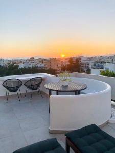 um pátio com uma mesa e cadeiras e um pôr-do-sol em Amazing Suite at Glyfada with sea view & jacuzzi em Atenas