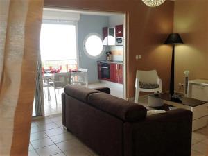 a living room with a brown couch and a kitchen at Le Colibri - T2 les pieds dans l'eau in Saint-François