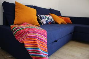 a blue couch with colorful pillows and a colorful blanket at El 8 de Serranos in León