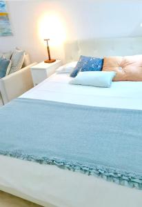 uma grande cama branca com um cobertor azul em Cosy loft in front of blue ocean em Las Palmas de Gran Canaria