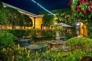 einen Garten mit Tischen, Stühlen und einem Brunnen in der Unterkunft Hotel Casa Antigua by AHS in Antigua Guatemala