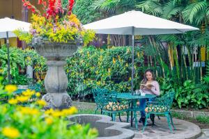 una mujer sentada en una mesa bajo un paraguas en Hotel Casa Antigua by AHS en Antigua Guatemala