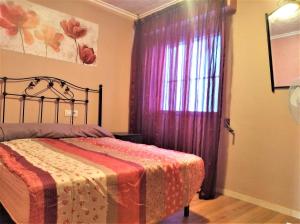 a bedroom with a bed and a window with purple curtains at San Blas Apartment - Alicante City in Alicante