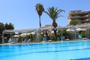 a pool with chairs and palm trees next to a building at Hotel Mirasole International in Gaeta