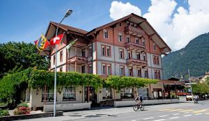 Ein Mann, der vor einem Gebäude Fahrrad fährt in der Unterkunft Hotel Sonne Interlaken-Matten in Interlaken