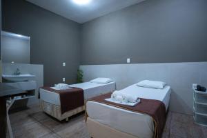 a bathroom with two beds and a sink and a mirror at Hotel BH Inn Palmares - Fácil Acesso Cristiano Machado, Centerminas e Minas Shopping in Belo Horizonte
