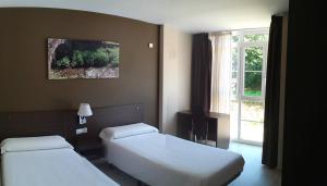 a hotel room with two beds and a window at Pension-Albergue Lemos in Treacastela