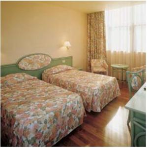 a hotel room with two beds and a chair at Hotel La Corte in Rubiera