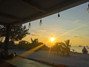 uma vista para o pôr-do-sol a partir de uma praia com luzes em Ocean Vista Maldives,Maafushi em Maafushi