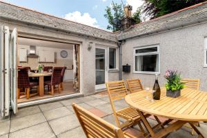 a patio with a wooden table and chairs at Dormie Cottage, lovely bright and spacious bungalow with wood fire in Ballater