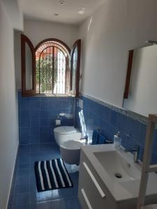 bagno piastrellato blu con servizi igienici e lavandino di Charming Place Taormina a Taormina