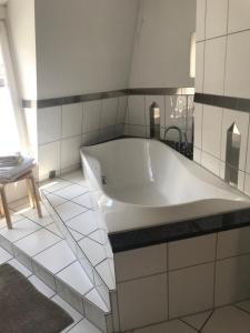 La salle de bains est pourvue d'une baignoire blanche et de carrelage blanc. dans l'établissement Best Location - Luxury Loft Riverview, à Heidelberg