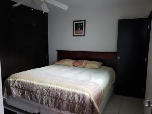 een slaapkamer met een bed en een zwarte kast bij Departamentos Mazatlán in Mazatlán