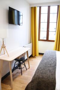 a hotel room with a bed, desk and television at Hotel Athanor Centre in Beaune
