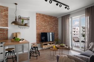 a kitchen and living room with a brick wall at Apartament Przystań Calamo in Olsztyn