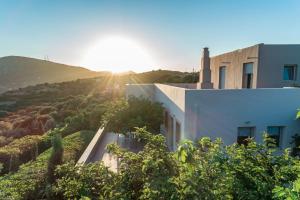 a house on a hill with the sun in the background at Villa Iris in Livadi