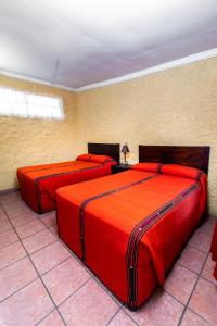 two beds in a room with red sheets at Hotel La Sin Ventura in Antigua Guatemala