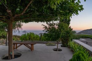 a wooden bench sitting next to two trees at Villa Iris in Livadi