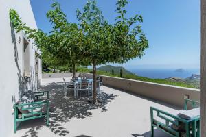 a patio with a table and chairs and a tree at Villa Iris in Livadi