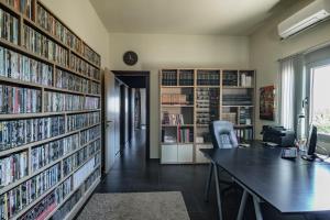 an office with a desk and a library with dvds at Villa Iris in Livadi