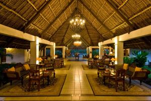 a resort lobby with tables and chairs and a chandelier at Karafuu Beach Resort & Spa in Pingwe