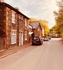 a car parked on a street next to a brick building at Woodland Cottage - private courtyard - Pet Friendly Retreat in the heart of Windermere in Windermere