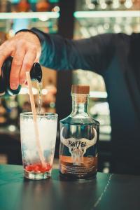 a person is pouring a drink into a glass at Dukes' Academie Brugge - by Dukes' Hotel Collection in Bruges