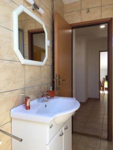 ein Badezimmer mit einem weißen Waschbecken und einem Spiegel in der Unterkunft Apartment Gotovina Biograd na Moru in Biograd na Moru