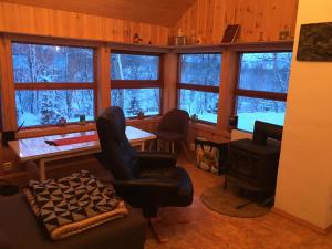 a living room with a chair and a table and windows at Kulpmo Gård Jarfjord-Kirkenes in Kirkenes