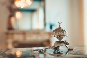 a small silver bell sitting on a glass table at Dukes' Academie Brugge - by Dukes' Hotel Collection in Bruges