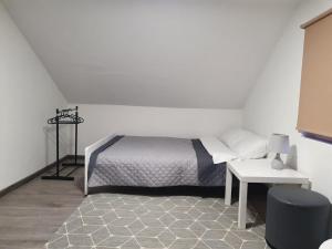 a white bedroom with a bed and a table at Zakątek w Zaciszu in Ustka