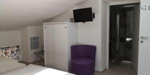 - une chambre avec une chaise violette et une télévision murale dans l'établissement B&B - Uva Residence, à Fano