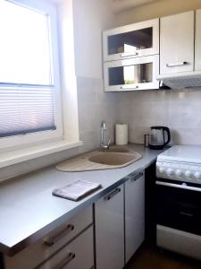a kitchen with white cabinets and a sink and a window at Apartament Gdańsk Szklana Huta in Gdańsk