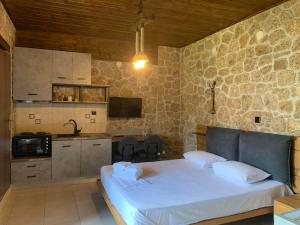 um quarto com uma cama branca e uma parede de pedra em Alexandros em Kato Loutraki