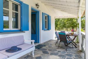 Un porche con un banco y una mesa con sillas. en Myrto Holiday House, en Stafylos