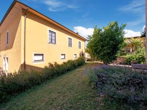 ein gelbes Gebäude mit einem Baum neben einem Hof in der Unterkunft Belvilla by OYO Casale Nuovo in Chianciano Terme