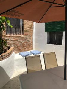 a table and chairs under an umbrella on a patio at La Casa Turquesa-Original in Frigiliana