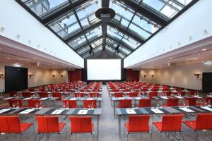 a large room with tables and chairs and a screen at Lindner Hotel Frankfurt Hochst, part of JdV by Hyatt in Frankfurt