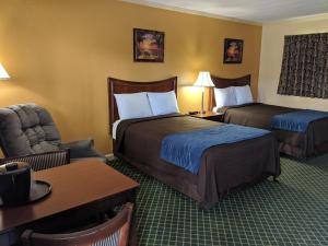 um quarto de hotel com duas camas e uma cadeira em Cheerio Inn - Glennville em Glennville