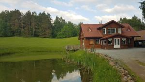 uma casa com um lago em frente em GRAŽINOS SODYBA em Telsiai